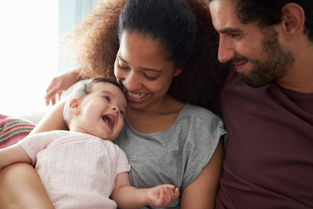 moeder en vader kijken zittend naar de pasgeboren baby